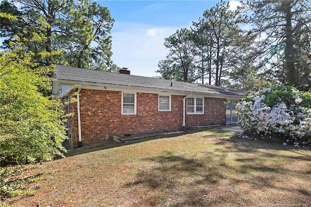 rear view of house with a lawn, brick siding, a chimney, and crawl space