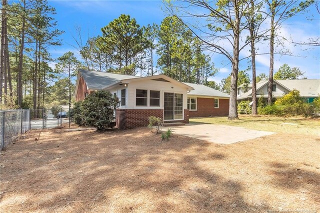 83 Pine Lake Dr, Whispering Pines, NC 28327 - rear view of property with brick siding, entry steps, a patio, and fence