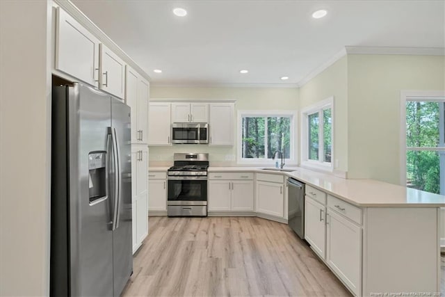 45 Martin Dr, Whispering Pines, NC 28327 - kitchen featuring stainless steel appliances, a peninsula, crown molding, white cabinetry, and light countertops