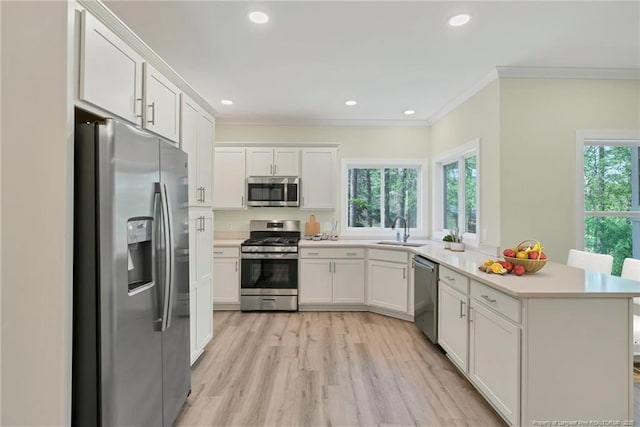 45 Martin Dr, Whispering Pines, NC 28327 - kitchen with stainless steel appliances, a peninsula, ornamental molding, light countertops, and white cabinets