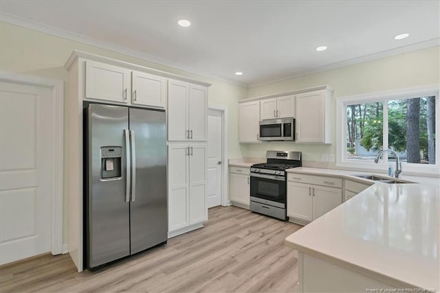 45 Martin Dr, Whispering Pines, NC 28327 - kitchen with appliances with stainless steel finishes, white cabinets, light countertops, light wood-style flooring, and ornamental molding