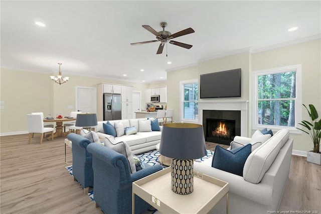45 Martin Dr, Whispering Pines, NC 28327 - living area featuring a chandelier, healthy amount of natural light, light wood finished floors, a lit fireplace, and ornamental molding