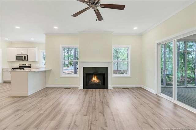45 Martin Dr, Whispering Pines, NC 28327 - unfurnished living room featuring ornamental molding, plenty of natural light, light wood-style floors, a warm lit fireplace, and recessed lighting