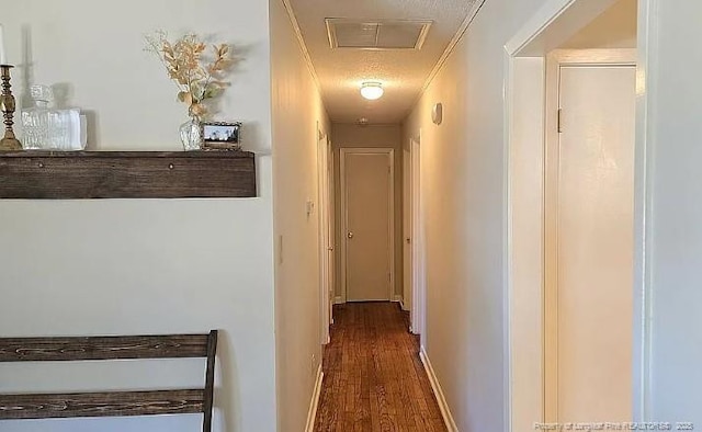 corridor featuring attic access, wood finished floors, visible vents, and crown molding