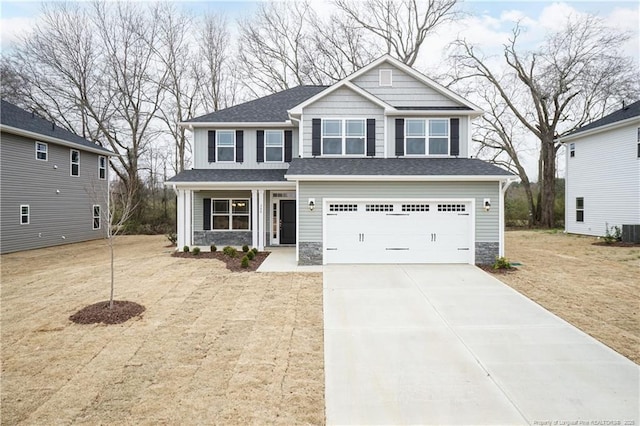 craftsman-style home featuring concrete driveway, central AC, stone siding, and a garage