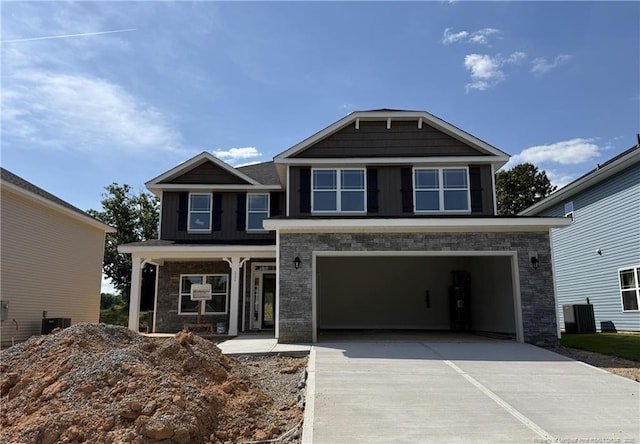 view of front of house featuring an attached garage, concrete driveway, stone siding, and cooling unit