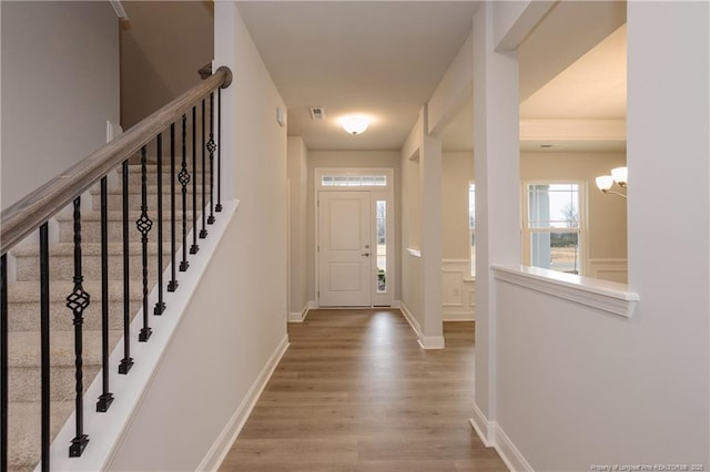 foyer entrance featuring baseboards, wood finished floors, and a chandelier