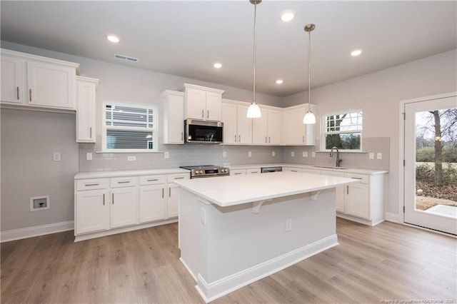 kitchen featuring white cabinets, a sink, light countertops, stainless steel appliances, and visible vents