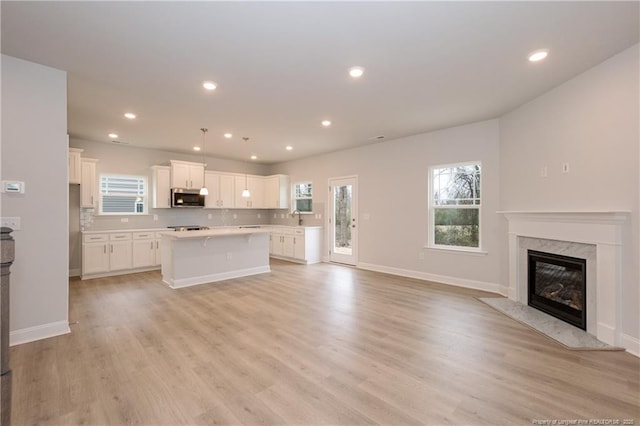 kitchen with a kitchen island, open floor plan, light countertops, white cabinetry, and appliances with stainless steel finishes