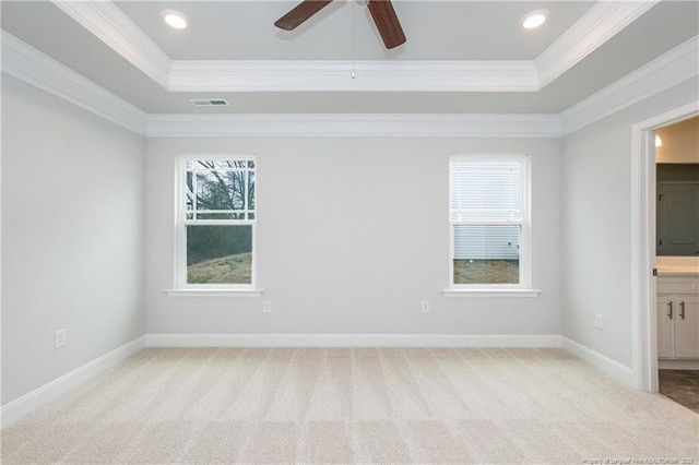 spare room with visible vents, a raised ceiling, crown molding, and light colored carpet