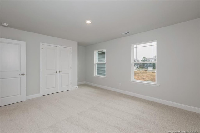 unfurnished bedroom featuring baseboards, carpet, a closet, and visible vents