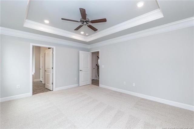 unfurnished bedroom featuring crown molding, ensuite bathroom, a tray ceiling, and light carpet