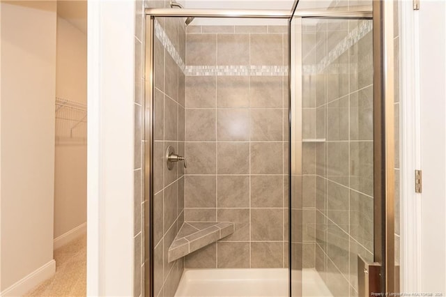 bathroom with baseboards, a spacious closet, and a shower stall