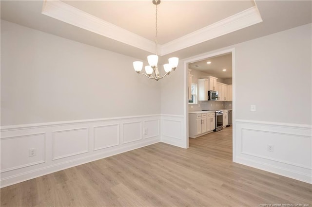 unfurnished dining area with a notable chandelier, ornamental molding, and a raised ceiling