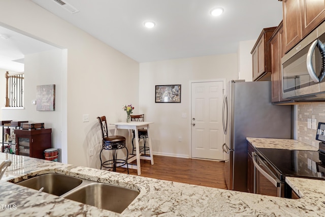 kitchen with wood finished floors, visible vents, light stone counters, and appliances with stainless steel finishes