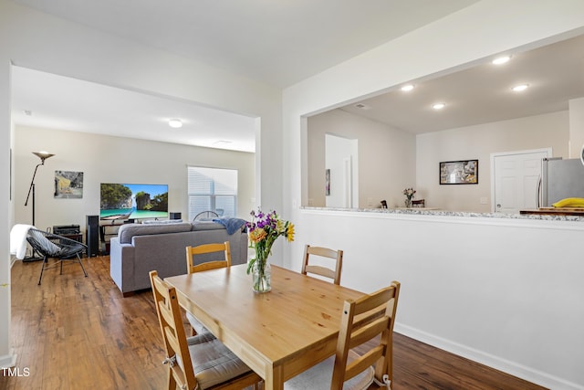 dining area with baseboards, wood finished floors, and recessed lighting
