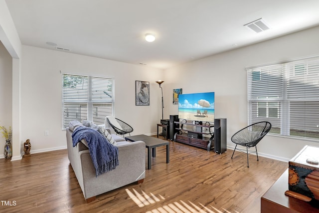 living area with baseboards, wood finished floors, and visible vents