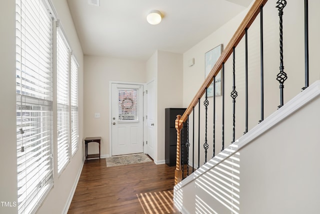 foyer entrance featuring baseboards, wood finished floors, and stairs