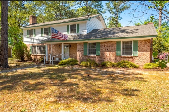 traditional-style home featuring a chimney, brick siding, and a front yard