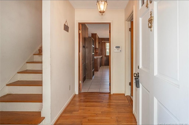 hall with stairway, baseboards, and light wood-style flooring