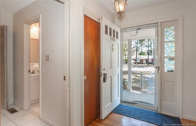 entryway featuring a chandelier, baseboards, and light tile patterned floors