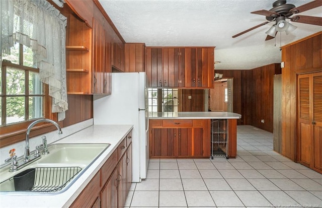 kitchen featuring wood walls, light countertops, open shelves, a sink, and brown cabinetry