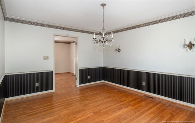 unfurnished room featuring crown molding and a wainscoted wall