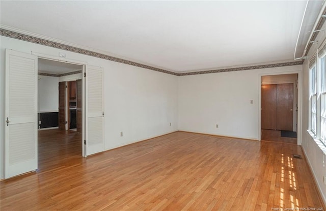 unfurnished room with crown molding, baseboards, a healthy amount of sunlight, and light wood-style floors