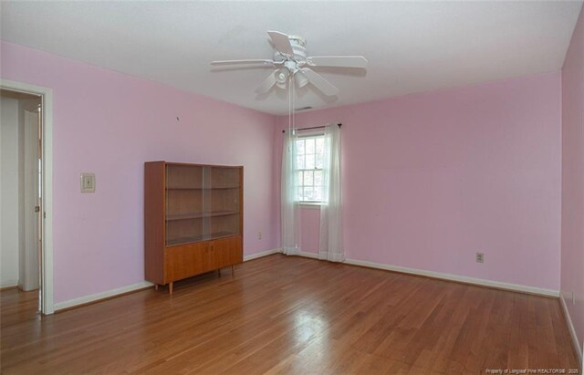 empty room featuring baseboards, wood finished floors, and ceiling fan