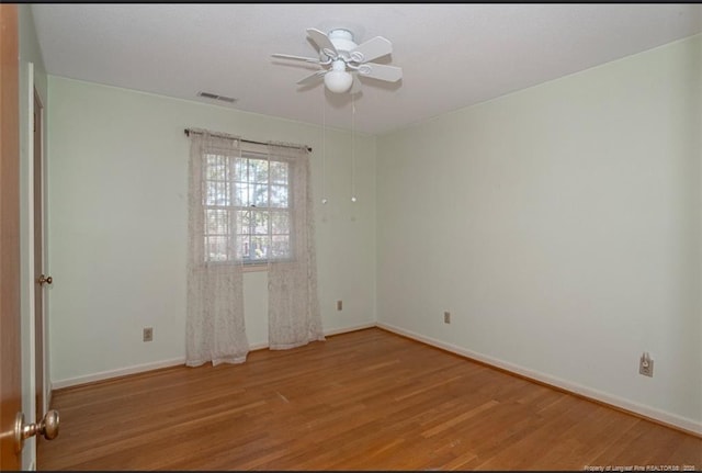empty room featuring baseboards, a ceiling fan, visible vents, and light wood-type flooring