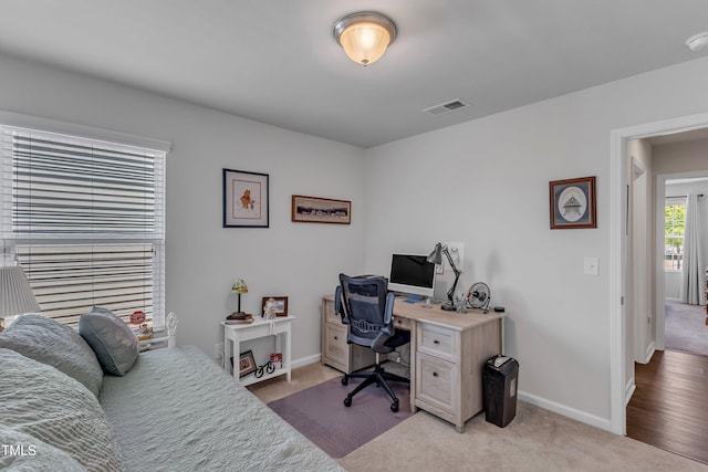 office area featuring baseboards and light carpet