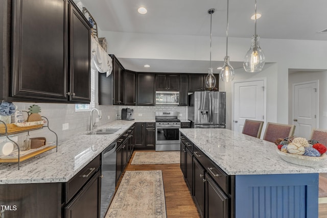 kitchen with appliances with stainless steel finishes, a sink, dark wood-style floors, a kitchen island, and backsplash
