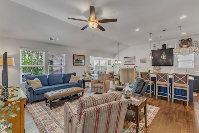 living area with lofted ceiling, plenty of natural light, dark wood-style flooring, and recessed lighting