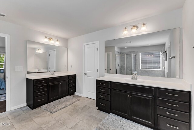 bathroom with a stall shower, two vanities, baseboards, and ensuite bathroom