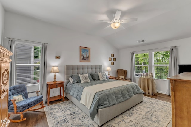 bedroom featuring wood finished floors, lofted ceiling, multiple windows, and a ceiling fan