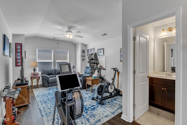 exercise area with a ceiling fan, a sink, lofted ceiling, wood finished floors, and baseboards