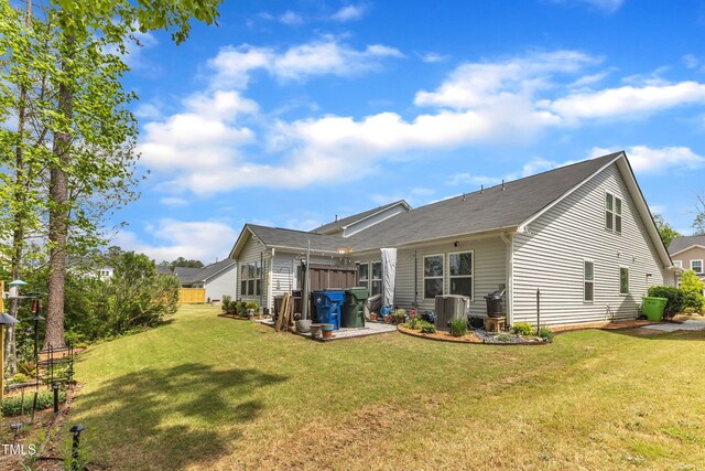 back of house featuring a lawn, a patio area, cooling unit, and a shingled roof