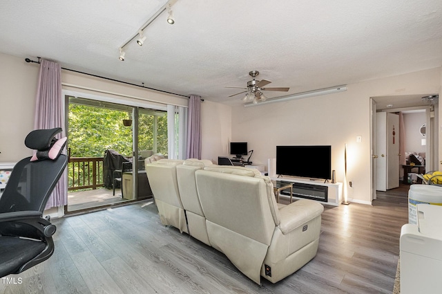 living room with a textured ceiling, a ceiling fan, and wood finished floors