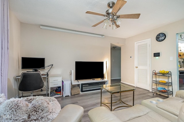 living area with a ceiling fan and wood finished floors
