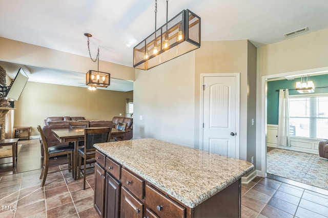 kitchen with hanging light fixtures, open floor plan, an inviting chandelier, light stone countertops, and visible vents