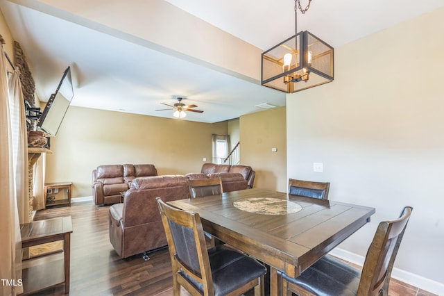 dining space with stairway, ceiling fan with notable chandelier, baseboards, dark wood-type flooring, and visible vents
