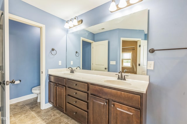 full bath featuring double vanity, toilet, baseboards, and a sink