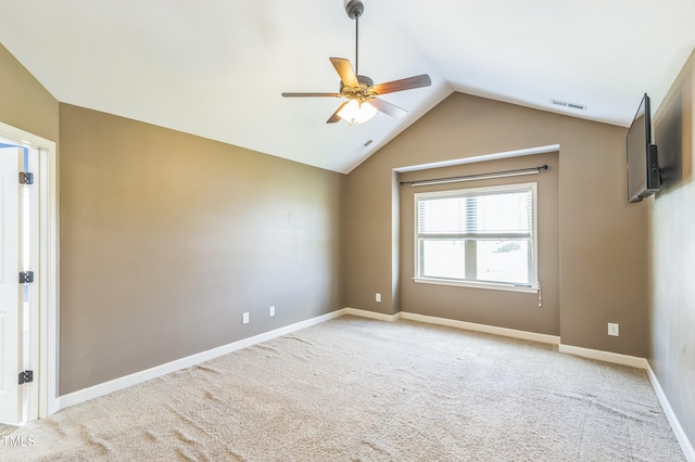 carpeted empty room featuring lofted ceiling, a ceiling fan, visible vents, and baseboards