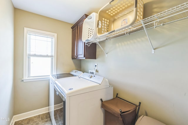 washroom with cabinet space, washing machine and clothes dryer, and baseboards