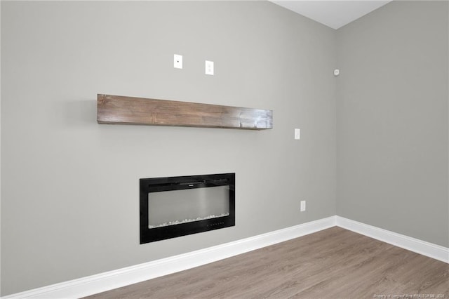 5566 Philippi Church Rd, Raeford, NC 28376 - unfurnished living room featuring wood finished floors, a glass covered fireplace, and baseboards