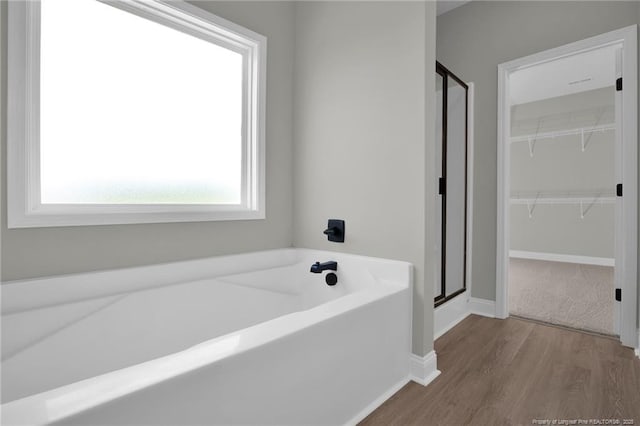 5566 Philippi Church Rd, Raeford, NC 28376 - bathroom with a stall shower, a garden tub, wood finished floors, and a spacious closet