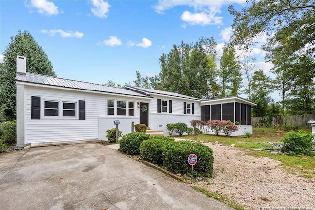 413 Lincoln Mckay Dr, Lillington, NC 27546 - view of front facade featuring a chimney, concrete driveway, fence, metal roof, and a sunroom