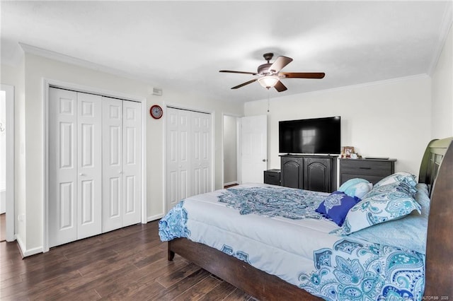 bedroom featuring wood finished floors, ornamental molding, baseboards, two closets, and ceiling fan