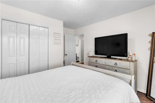 bedroom featuring baseboards, dark wood-type flooring, and a closet
