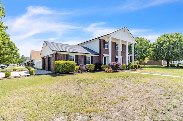neoclassical home featuring an attached garage, brick siding, and a front yard